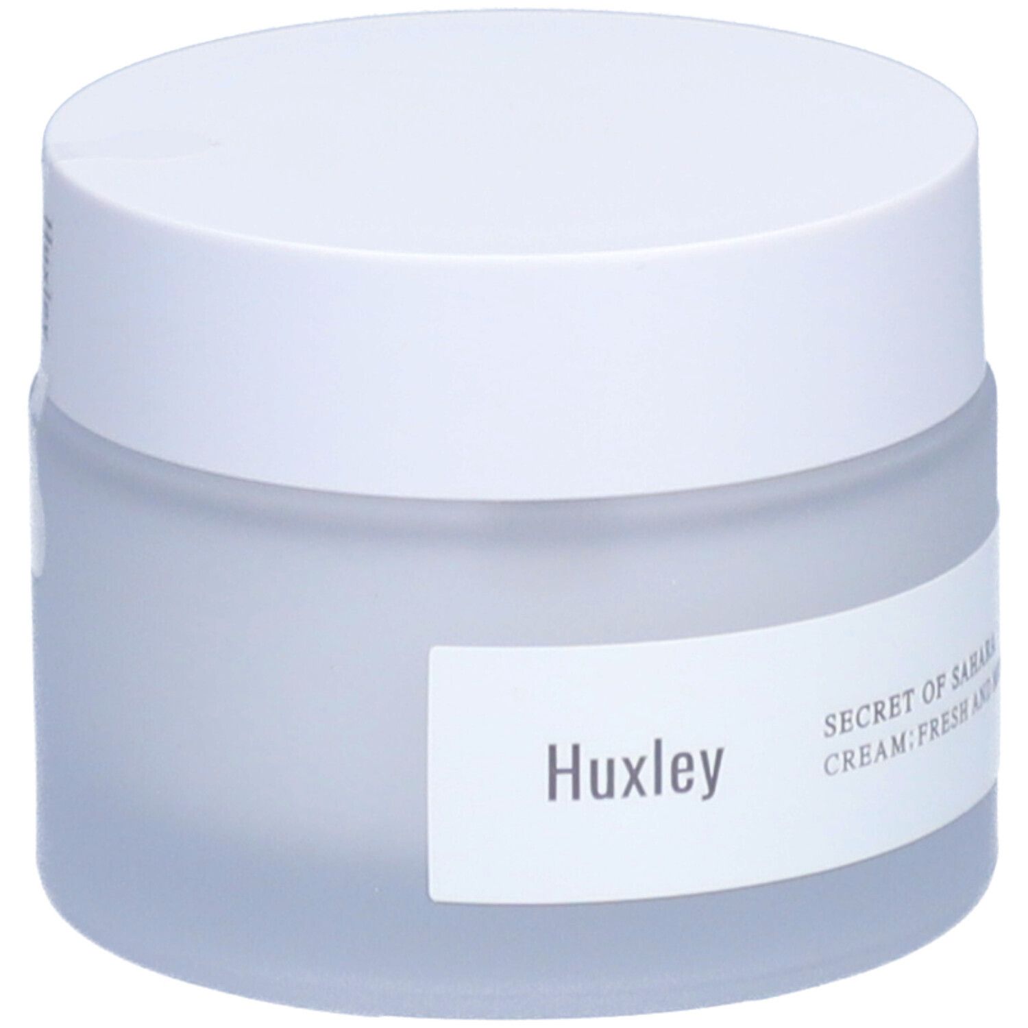 Pot de crème avec couvercle blanc. L'étiquette indique Huxley et Secret of Sahara Cream Fresh And More.