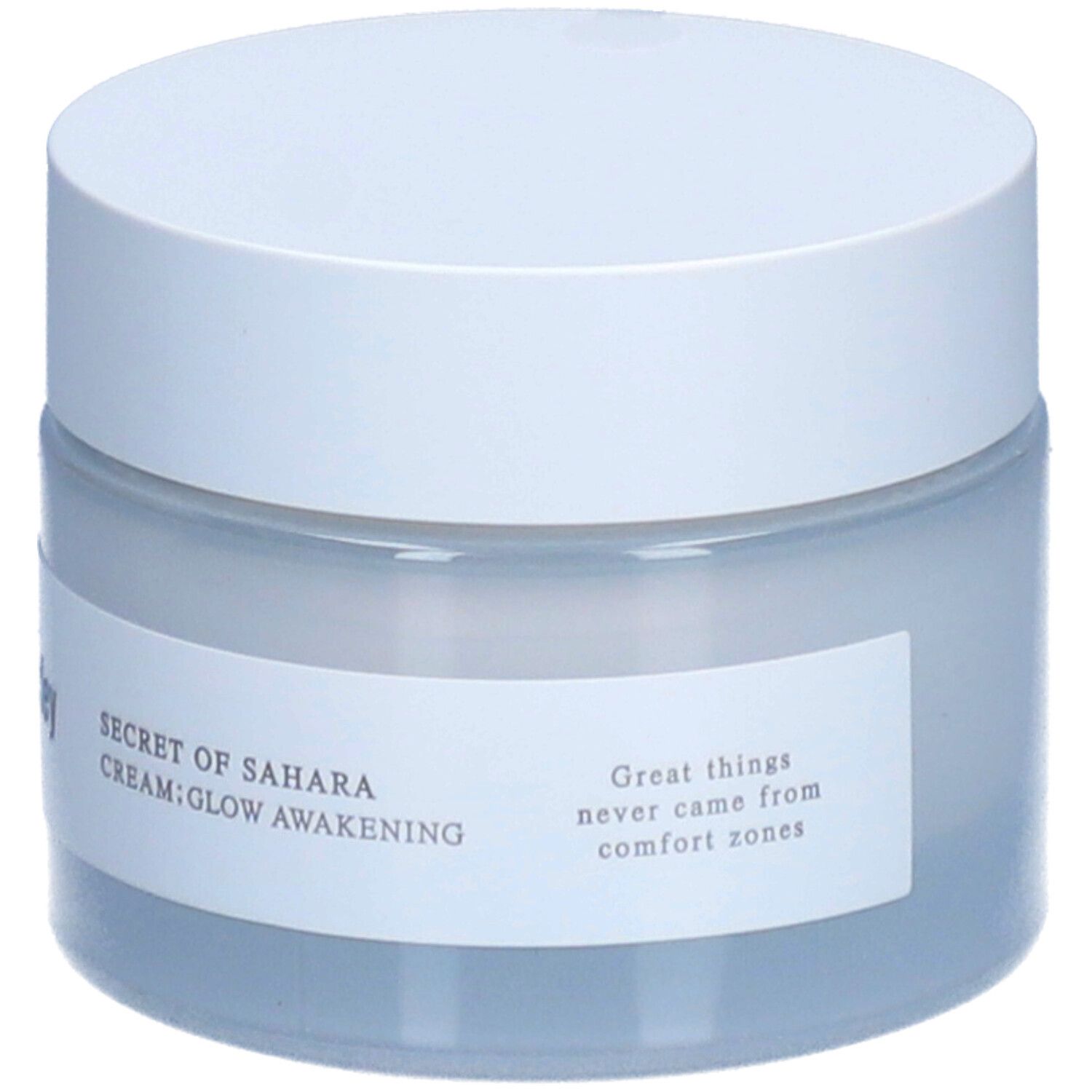 Pot de crème avec couvercle blanc. Étiquette avec texte: "SECRET OF SAHARA CREAM; GLOW AWAKENING" et citation.