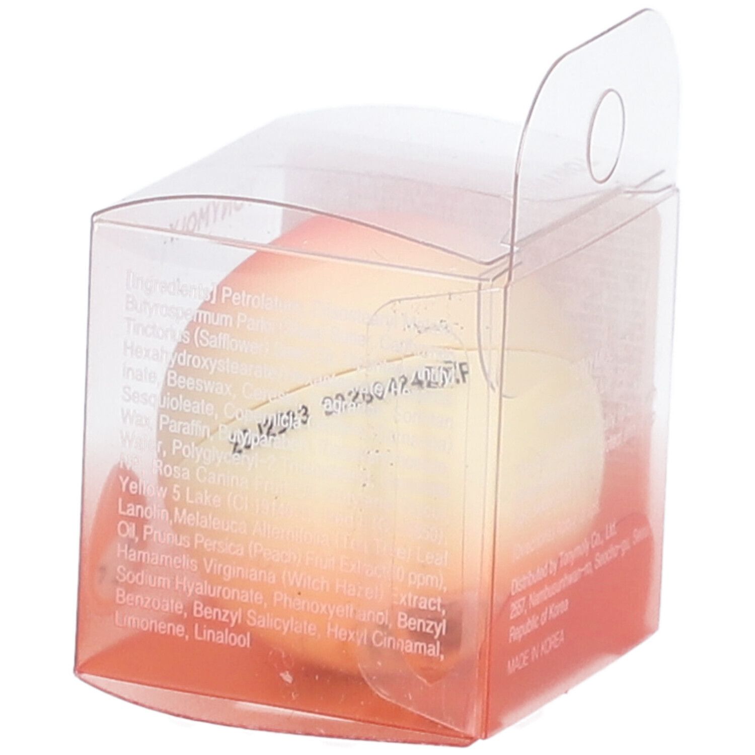 Baume à lèvres en forme de pêche dans un emballage transparent. Inscription : MINI PEACH LIP BALM. Texte sur l'emballage. Date de fabrication.