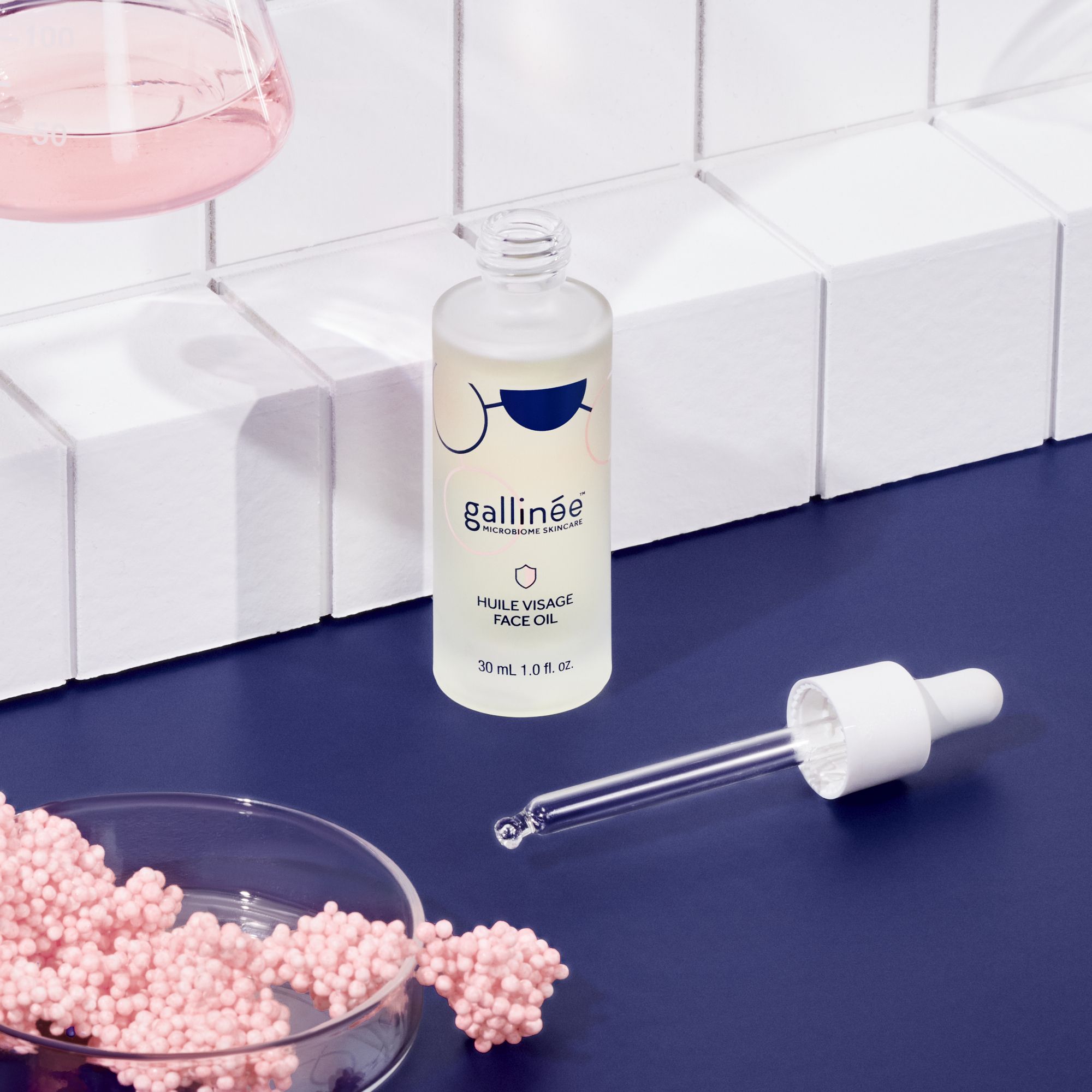 Flacon d'huile visage avec pipette et billes roses. Inscription : Huile Visage Face Oil. 30 ml.