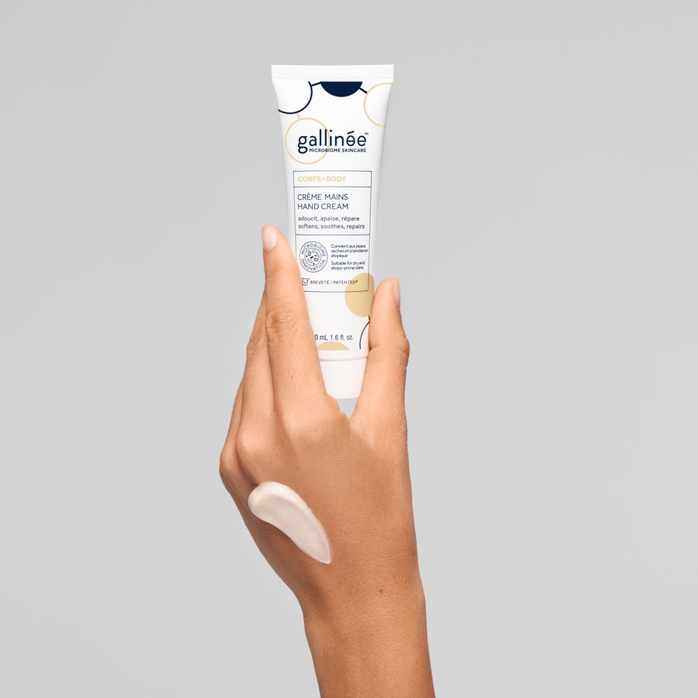 Une main tient un tube de crème pour les mains de la marque Gallinée. De la crème est appliquée sur le dos de la main.