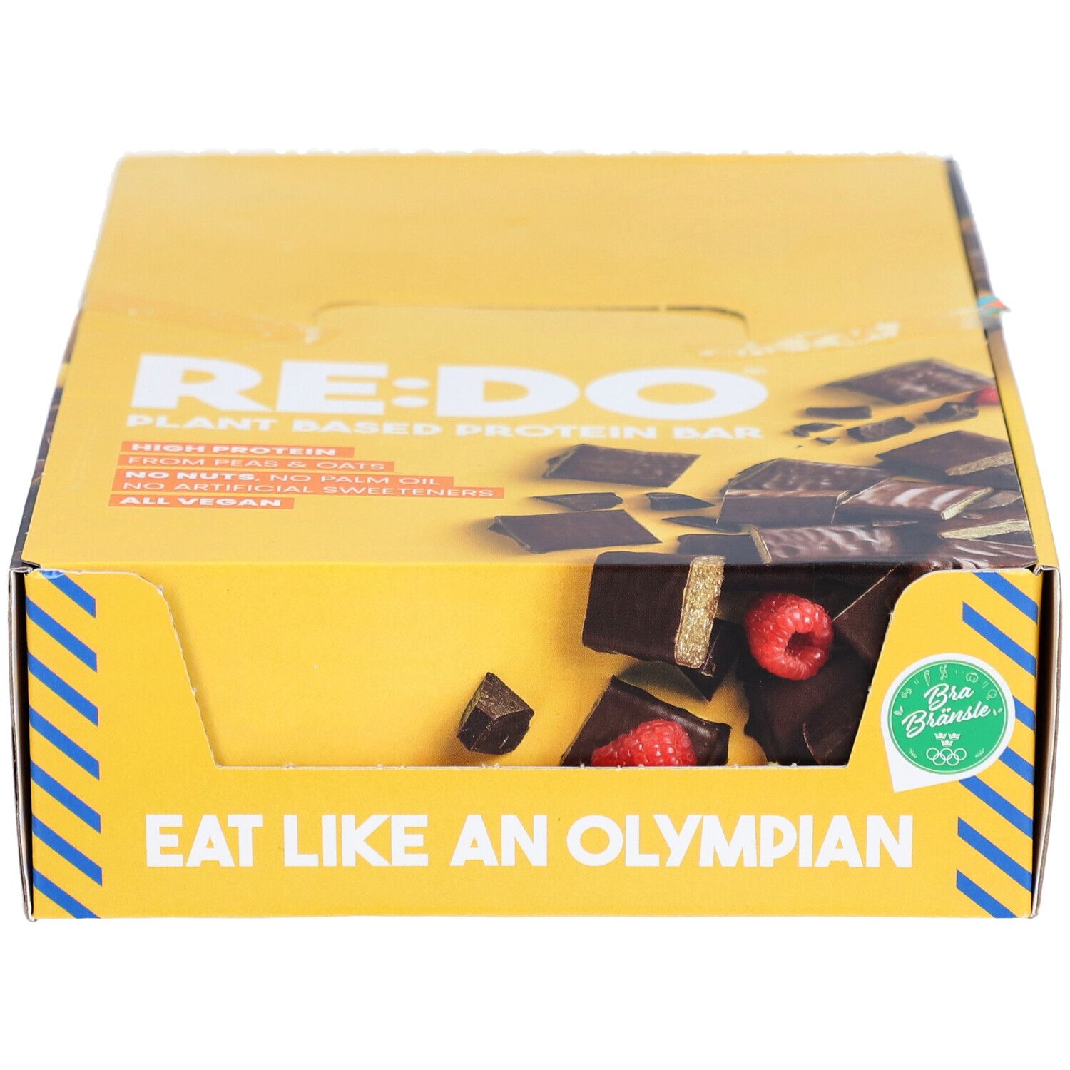 Boîte jaune avec logo RE:DO et texte. Morceaux de barres avec framboises visibles. Inscription : Eat like an Olympian.