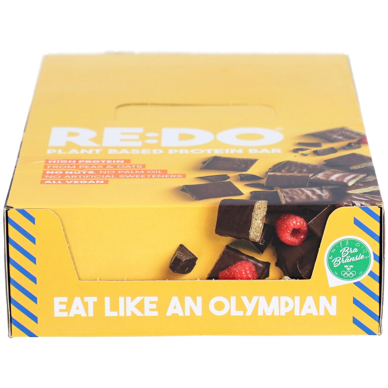 Boîte jaune de barres chocolatées RE:DO. Inscription : Plant Based Protein Bar. Visible : morceaux de barres avec framboises. Inscription : Eat like an Olympian. Vegan.