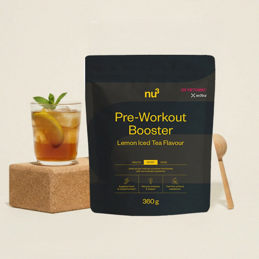 Emballage noir "nu3 Pre-Workout Booster" à côté d'un verre, cuillère en bois. Goût thé glacé citron.