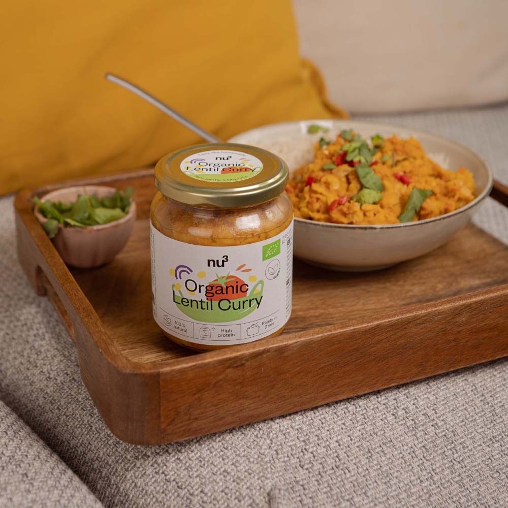 Pot de nu3 Organic Lentilles au curry sur un plateau en bois. À côté, un bol de menthe et un bol de riz et curry.