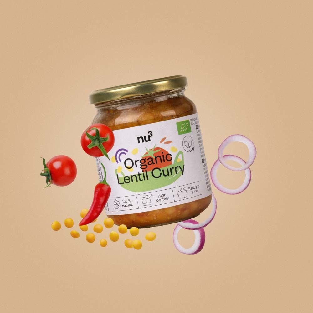 Pot de nu3 Organic Lentil Curry, entouré de tomates, piments et rondelles d'oignons.