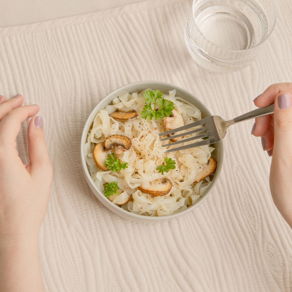 Un bol de nu3 Fit Konjak Tagliatelle avec champignons et persil, mangé à la fourchette.