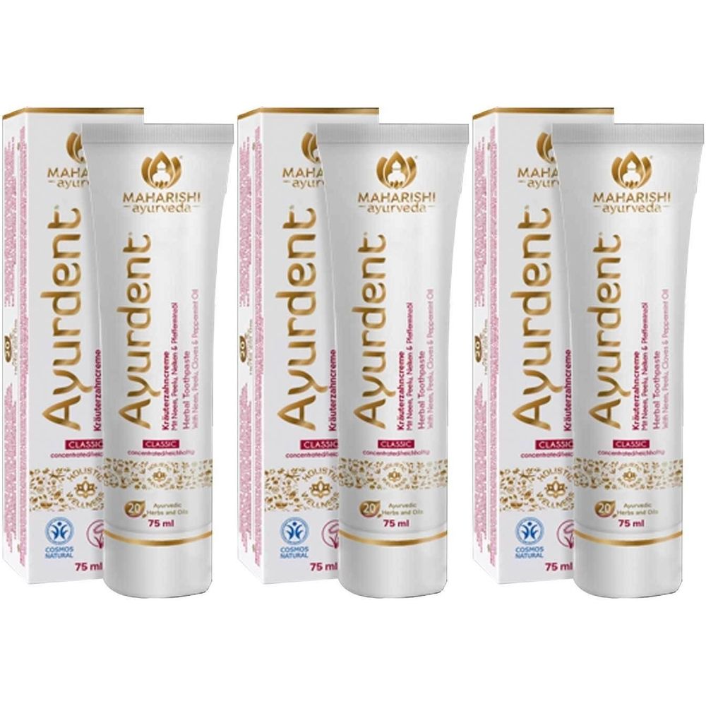 Plusieurs tubes et boîtes de dentifrice Ayurdent Classic. Les tubes sont blancs avec des accents dorés et rouges. Inscriptions : marque, nom du produit, ingrédients.