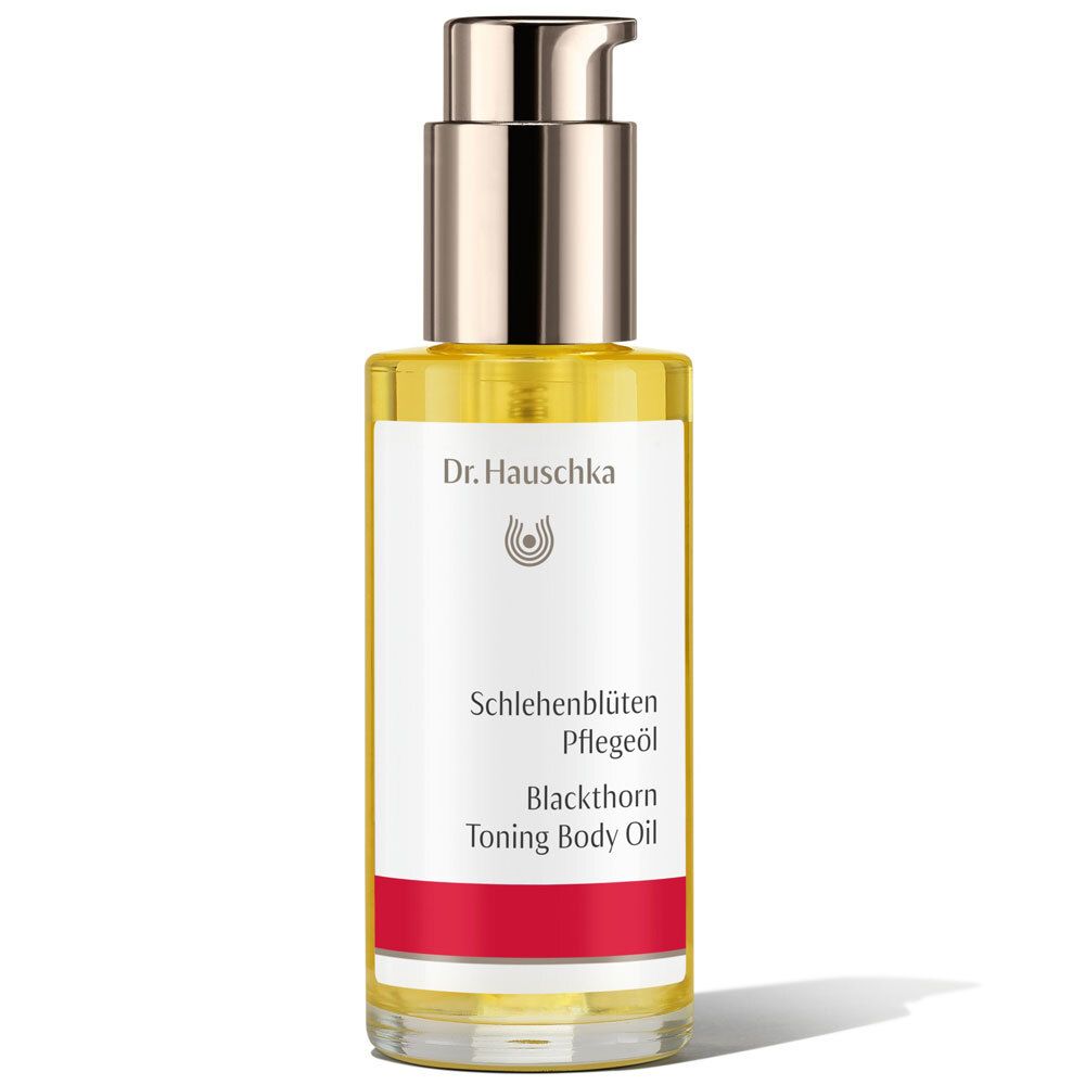 Flacon d'huile pour le corps avec pompe doseuse. Étiquette avec nom du produit et marque. Liquide jaune visible.