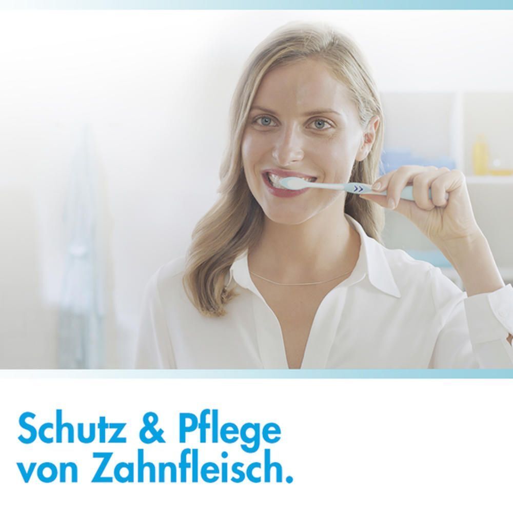 Une femme se brosse les dents avec une brosse à dents. Texte : Protection et soin des gencives.