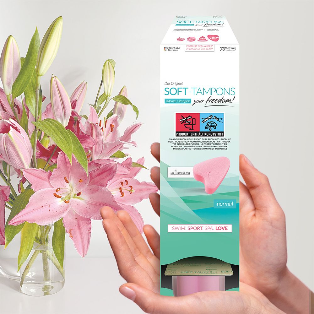 Soft Tampons Normal, emballage dans des mains, avec arrangement floral.