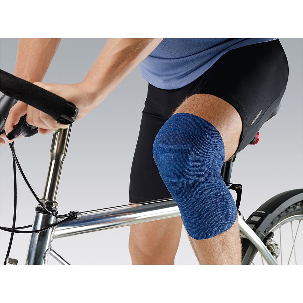 Personne assise sur un vélo, avec un bandage bleu autour du genou. Le bandage est enroulé autour du genou.