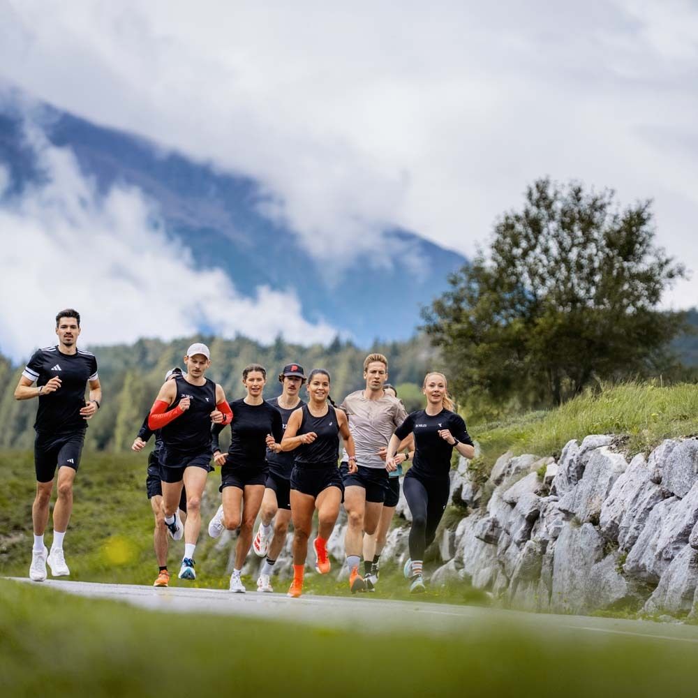Groupe de coureurs sur une route. Vêtements de sport. Montagnes et ciel en arrière-plan. Jour ensoleillé.