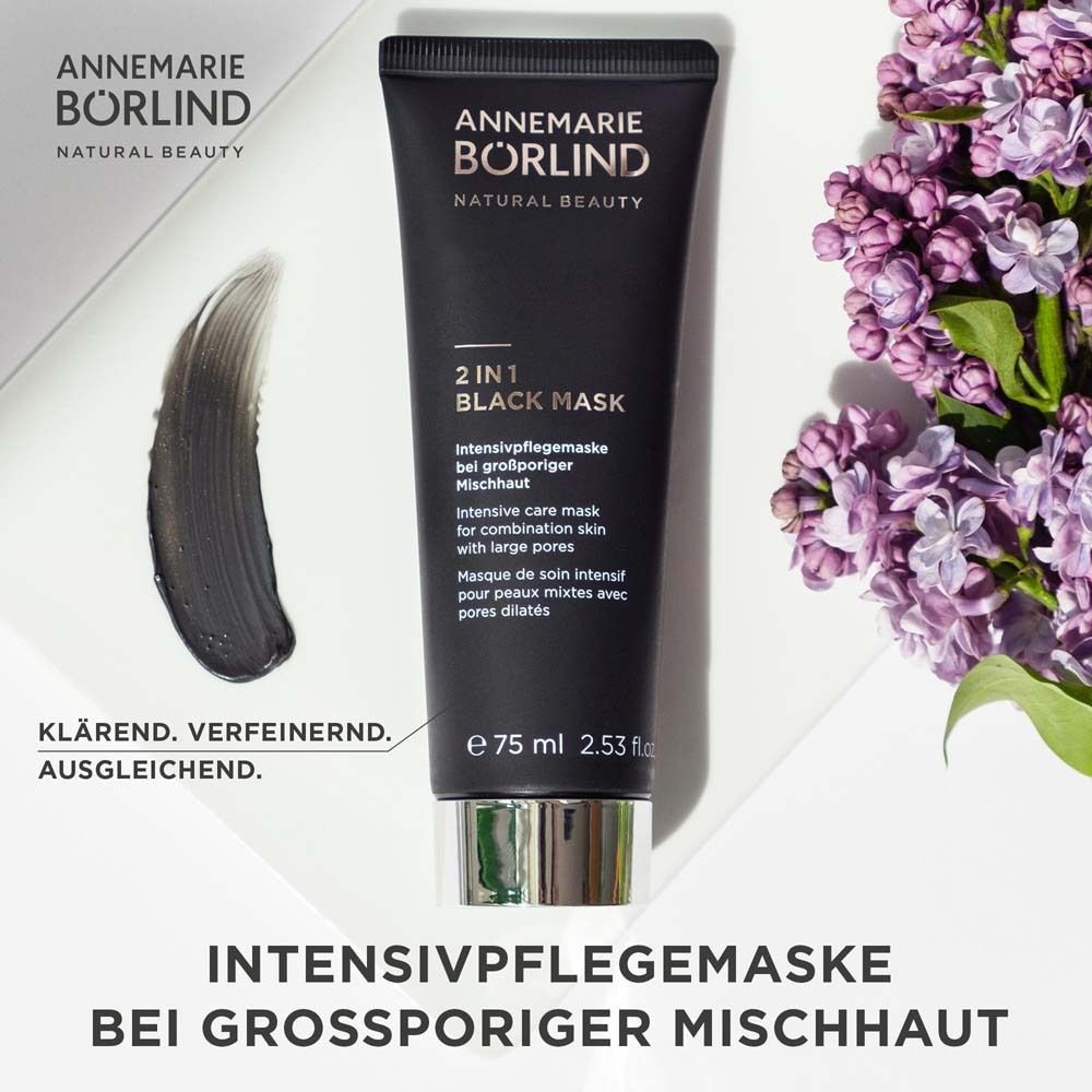 Tube noir avec texte du produit. Marque : ANNEMARIE BÖRLIND. Produit : 2 IN 1 BLACK MASK. Texte et fleurs.