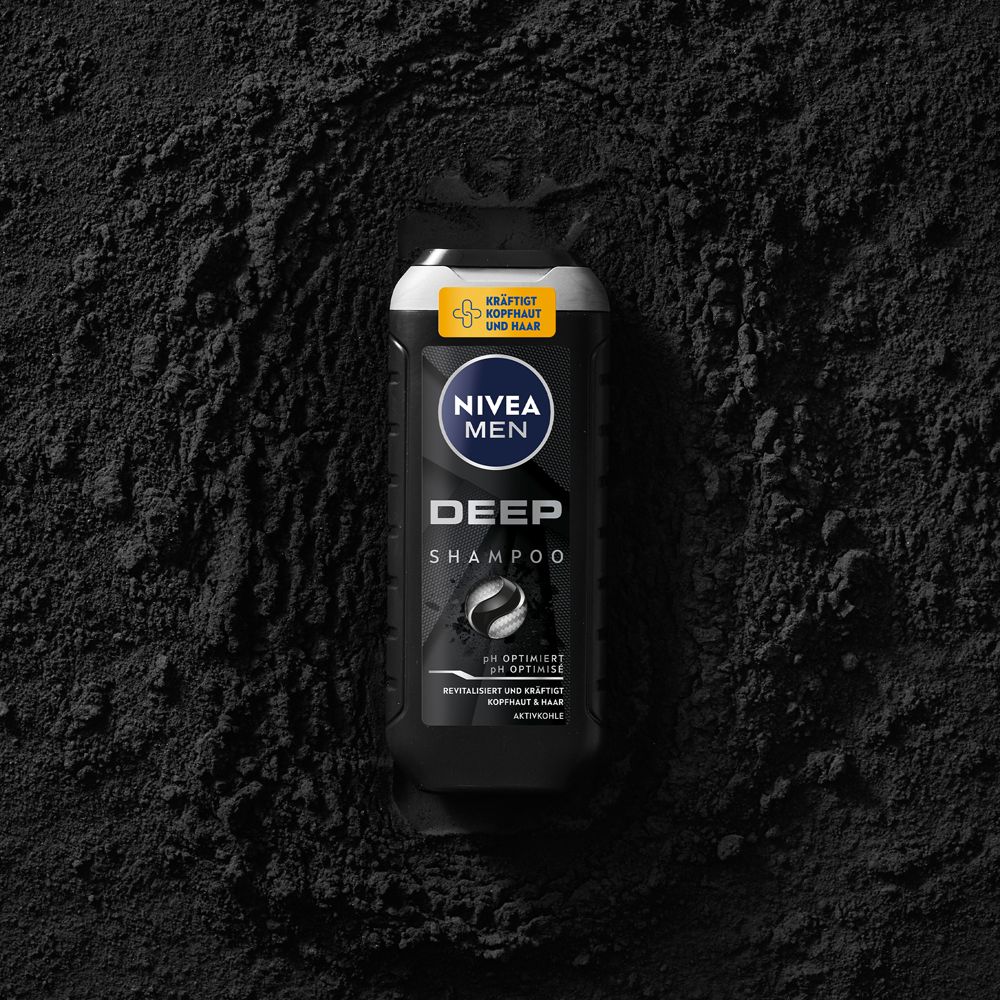 Flacon NIVEA MEN DEEP Shampoo posé dans une poudre noire symbolisant le charbon actif.