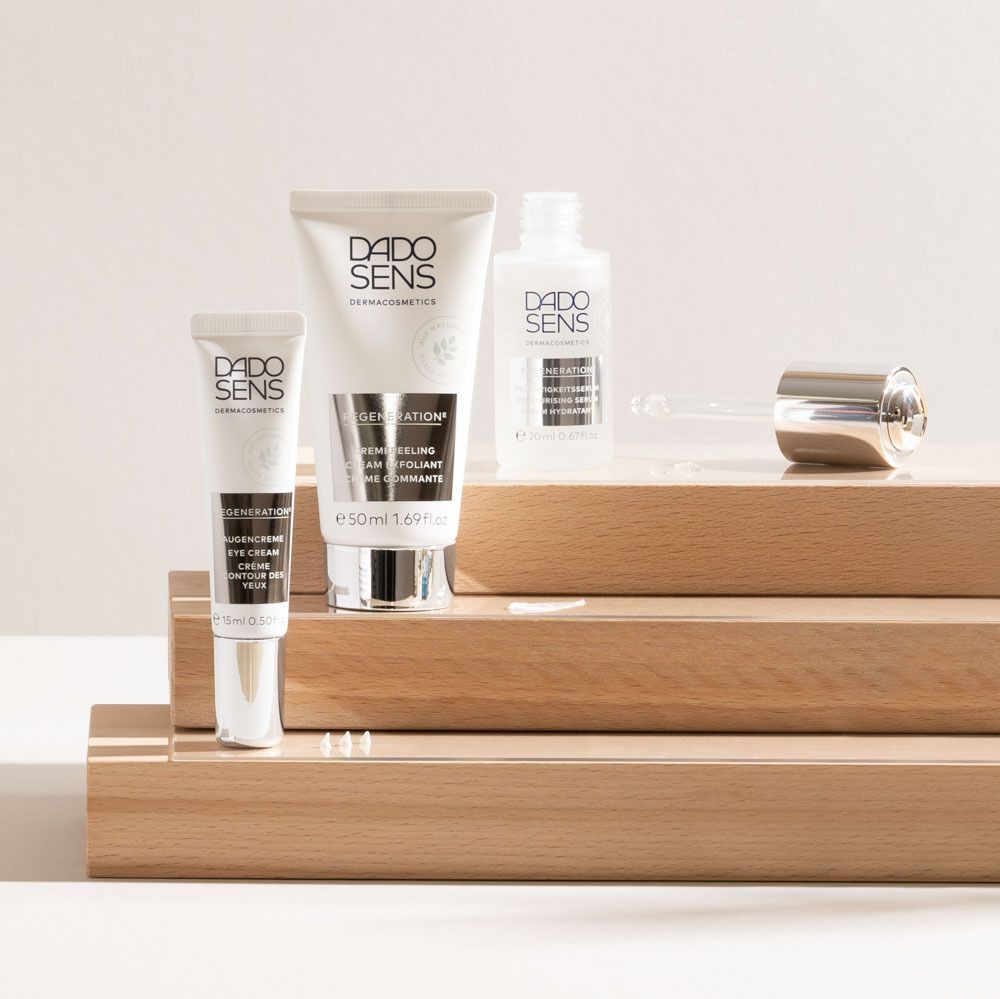 Différents produits DADO SENS sur des marches en bois. Sérum, crème, crème pour les yeux.