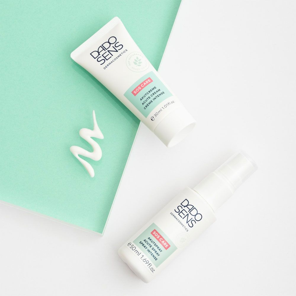 Deux tubes et un flacon pulvérisateur. DADO SENS SOS CARE Akutcreme et spray. Fond : turquoise.