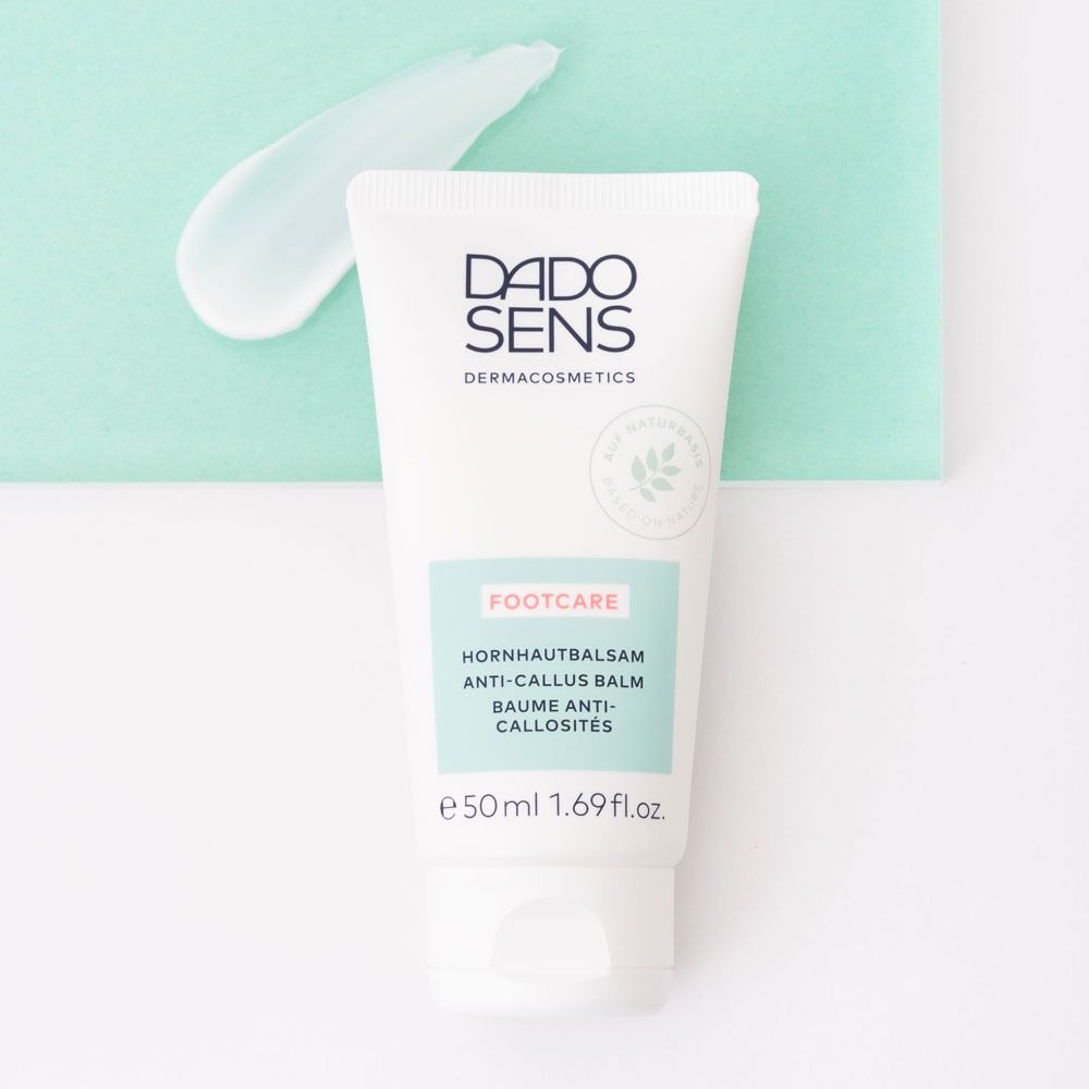 Tube blanc avec logo DADO SENS et FOOTCARE. Contient un baume anti-callosités. Sur fond vert.