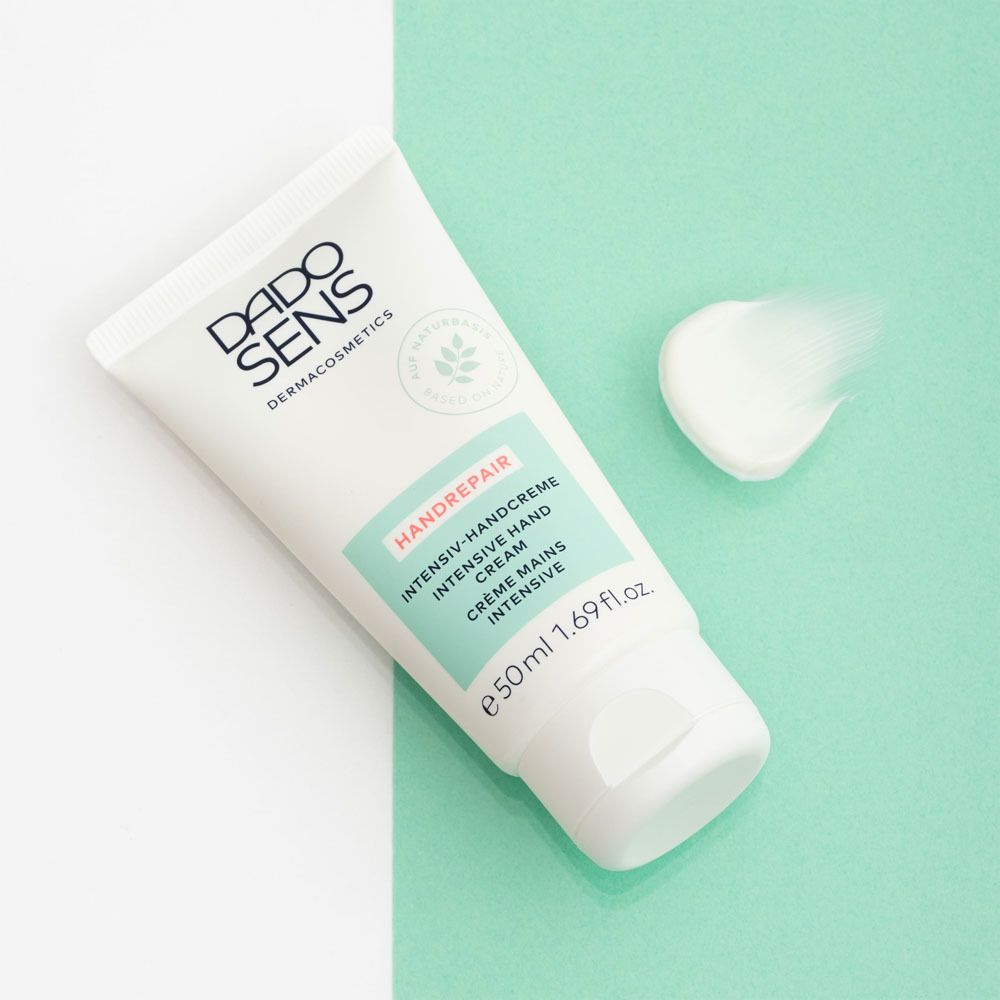 Tube DADO SENS Handrepair, crème mains intensive, sur fond vert. À côté, une noisette de crème.