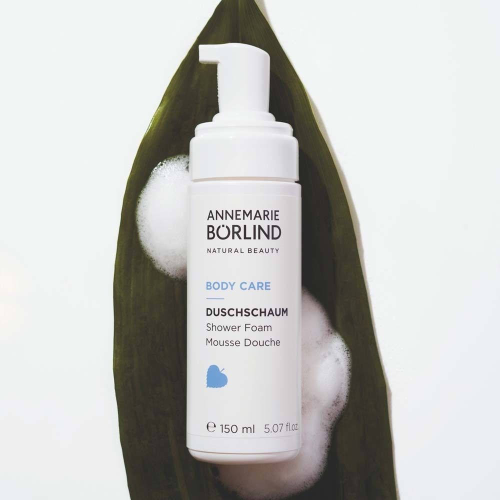 Flacon blanc avec pompe sur feuille. Inscription : ANNEMARIE BÖRLIND, BODY CARE, DUSCHSCHAUM, 150 ml.