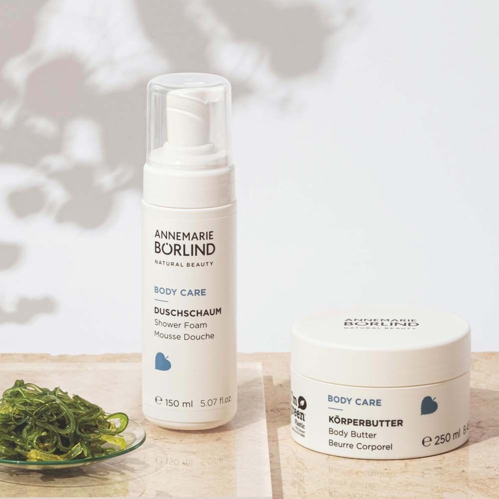 Flacon et pot blancs. Inscription : ANNEMARIE BÖRLIND, BODY CARE, DUSCHSCHAUM, 150 ml. Et beurre corporel.