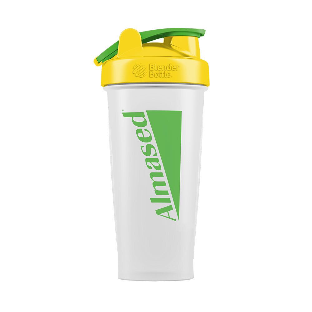 Shaker transparent avec couvercle jaune et fermeture verte. Inscription verte "Almased".
