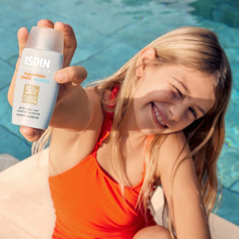 Une fille tient un flacon bleu ISDIN FusionWater Magic Pediatrics.