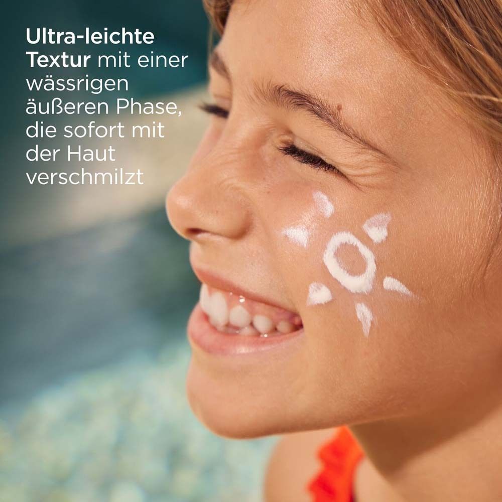 Visage d'une fille avec de la crème solaire en forme de soleil.