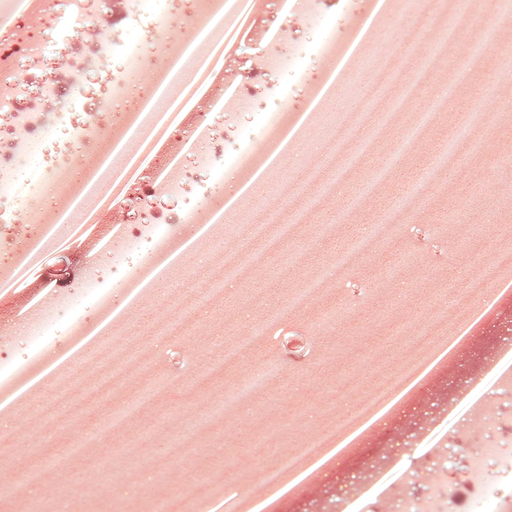 Gros plan sur gel douche rose. Texture avec petites bulles. Surface lisse et ondulée.