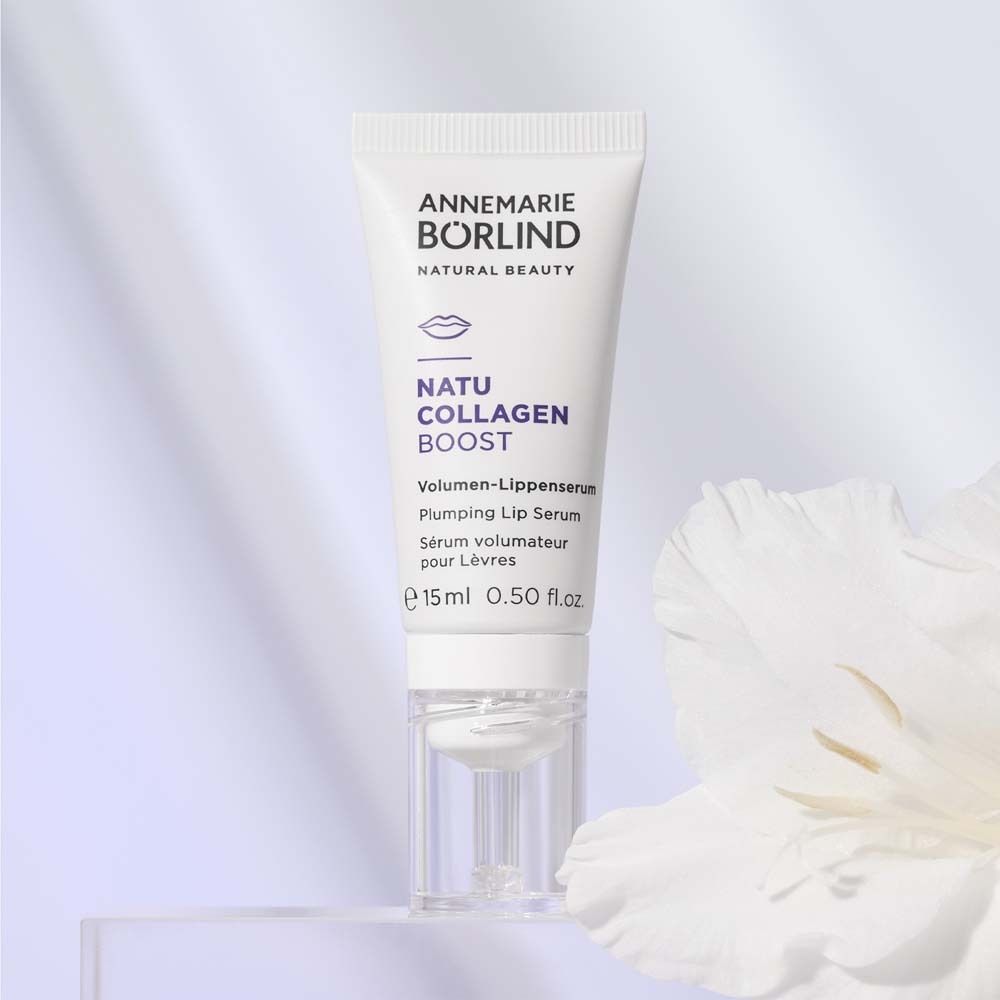 Sérum pour les lèvres blanc avec texte. Marque : ANNEMARIE BÖRLIND. Nom du produit : NATU COLLAGEN BOOST. Avec fleur en arrière-plan.