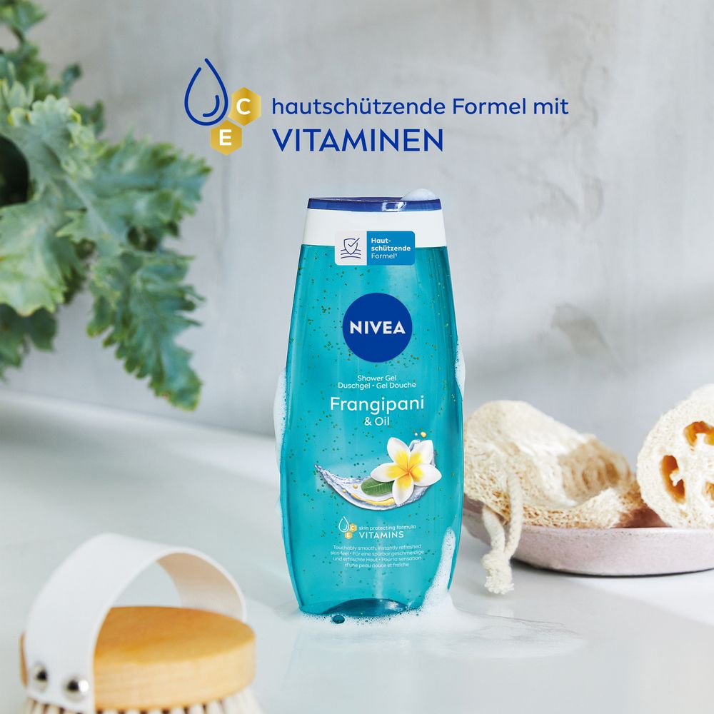 NIVEA Frangipani & Oil Douche Soin dans un cadre naturel avec plantes et accessoires de bain. Formule aux vitamines mise en avant.