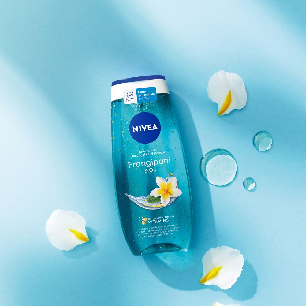 NIVEA Frangipani & Oil Douche Soin sur fond bleu avec des pétales de fleurs et des gouttes d'eau.