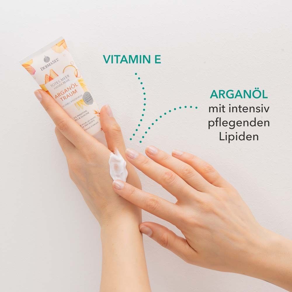 Mains avec crème. Texte: Vitamine E, huile d'argan avec lipides nourrissants. Tube de crème en arrière-plan.