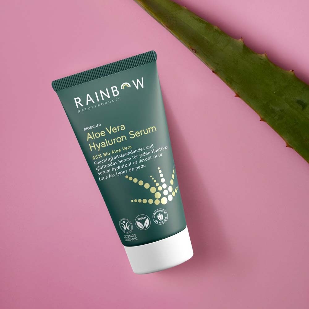 Tube vert sur disque en bois. Fond: vert clair. Produit: Aloe Vera Hyaluron Serum. Labels vegan et bio.
