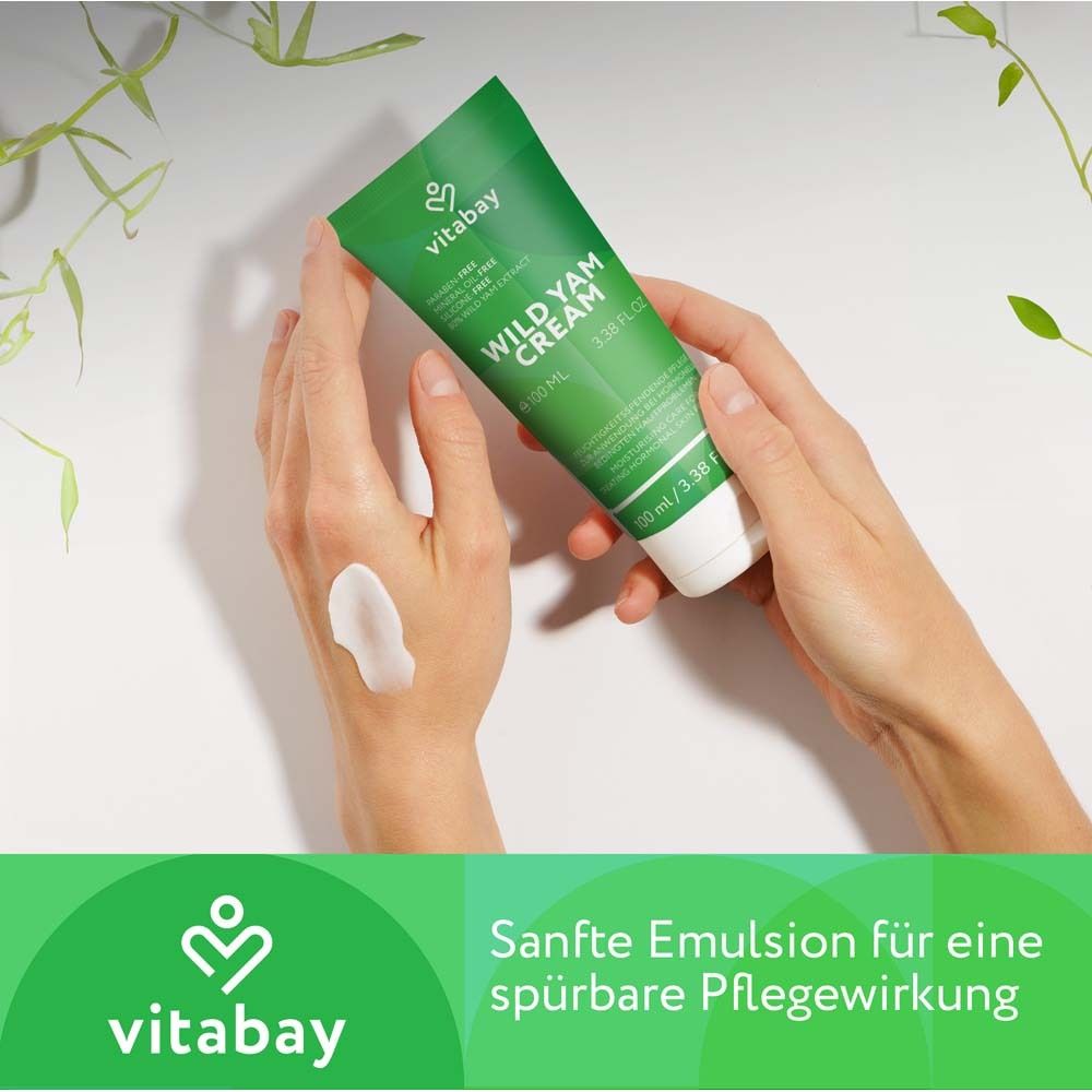 Mains avec crème. Tube vert "Wild Yam Cream". Texte : "Émulsion douce pour un soin perceptible".