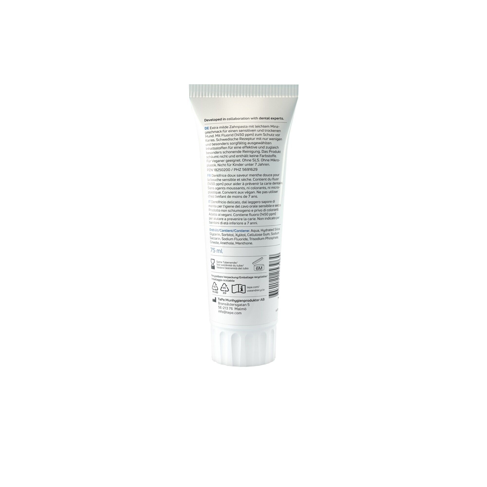 Dos d'un tube de dentifrice blanc. Texte en plusieurs langues. Informations sur les ingrédients et l'utilisation.