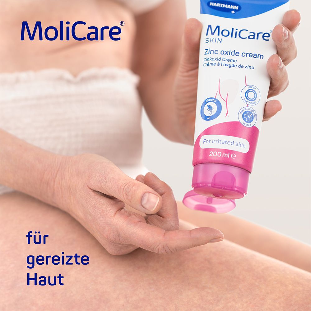 Personne tenant un tube de crème MoliCare Skin à l'oxyde de zinc. Inscription : Crème à l'oxyde de zinc. Texte : Pour peau irritée. Bouchon rose.