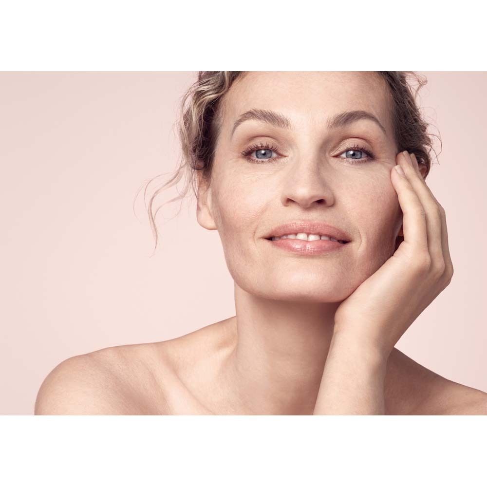 Portrait d'une femme avec une peau légèrement rouge. Elle touche son visage avec sa main.