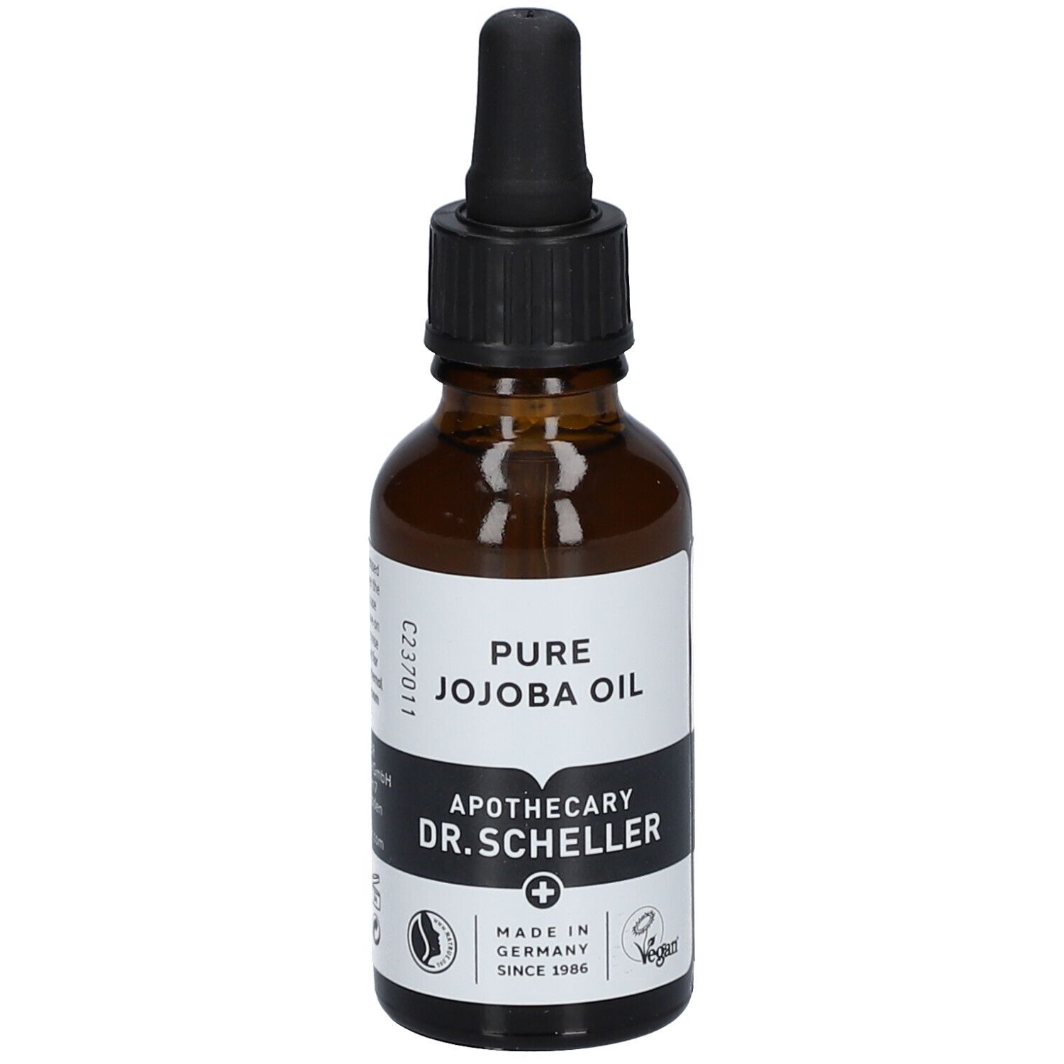 Flacon en verre brun avec pipette. Étiquette avec texte: PURE JOJOBA OIL, Apotheker DR.SCHELLER. Vegan. Fabriqué en Allemagne.