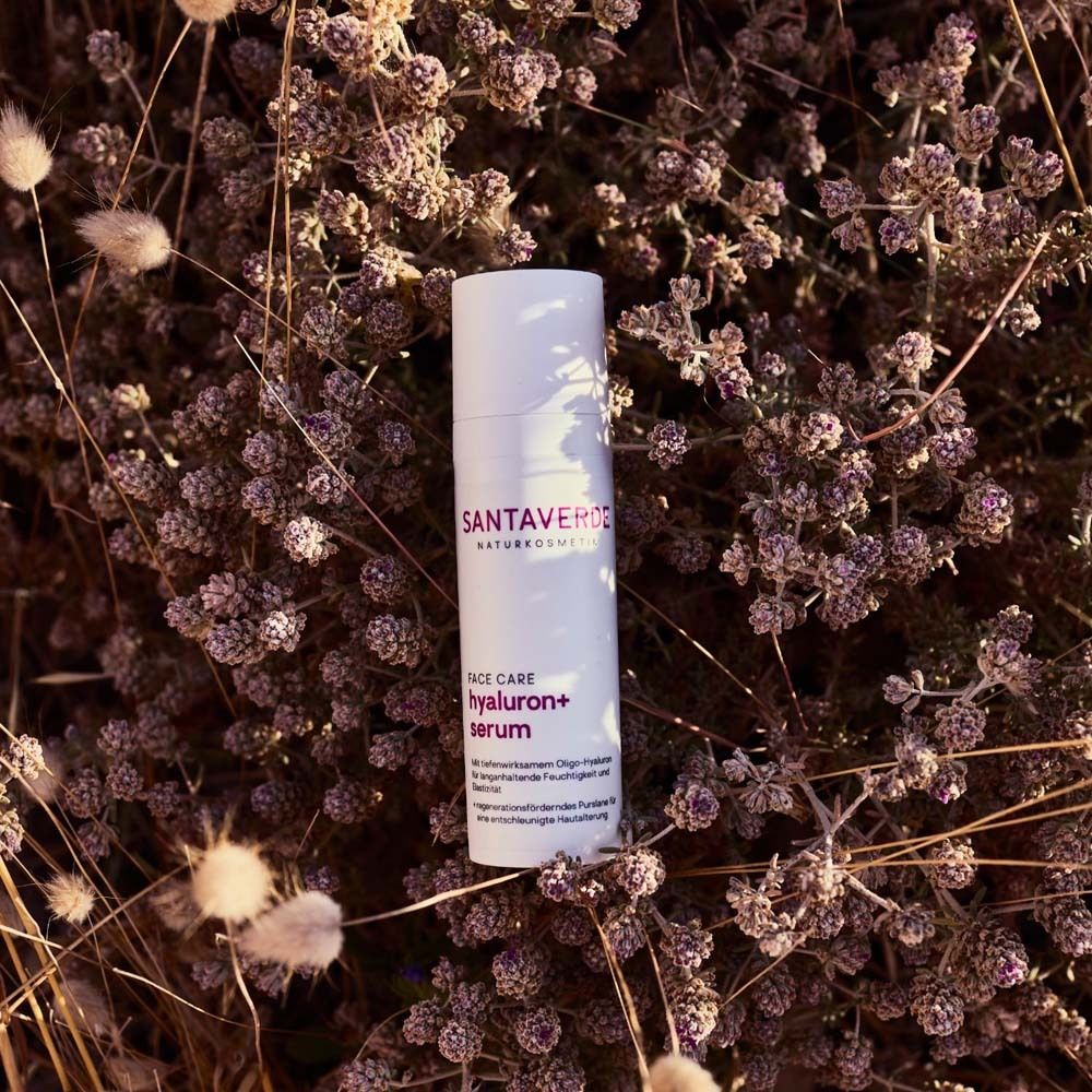 Flacon blanc avec nom du produit, placé dans des fleurs. Sérum pour le visage.