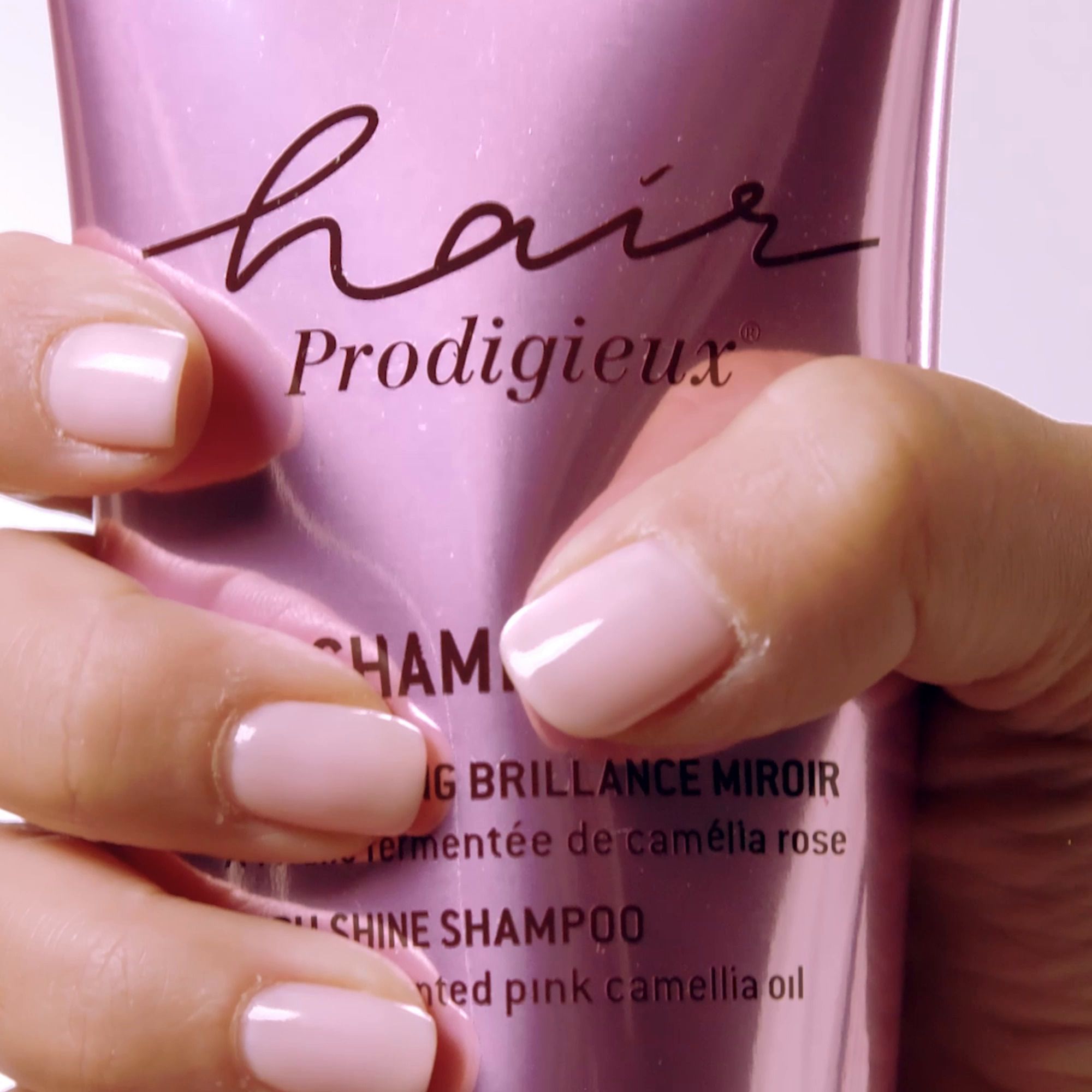 Main tenant un tube de shampooing NUXE Hair Prodigieux. Inscription et nom du produit.