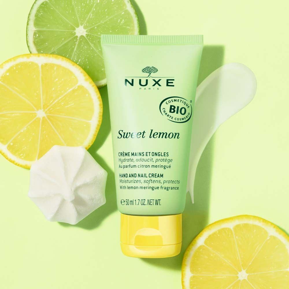 Tube de crème pour les mains vert avec bouchon jaune. Citrons et meringue en arrière-plan. Logo Nuxe et "Sweet lemon".