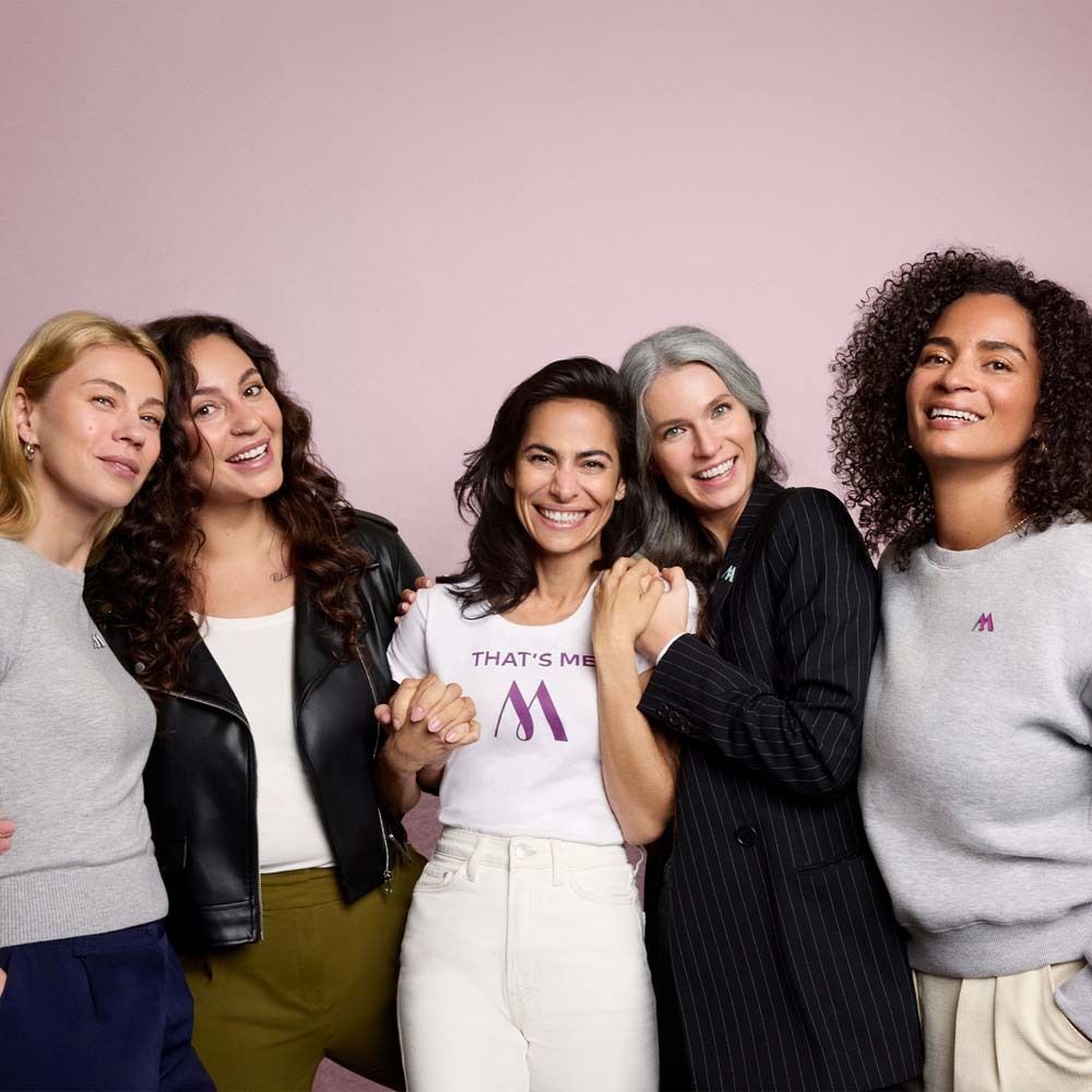Cinq femmes ensemble. Une porte un t-shirt blanc avec un logo. Inscription : THAT'S ME M.