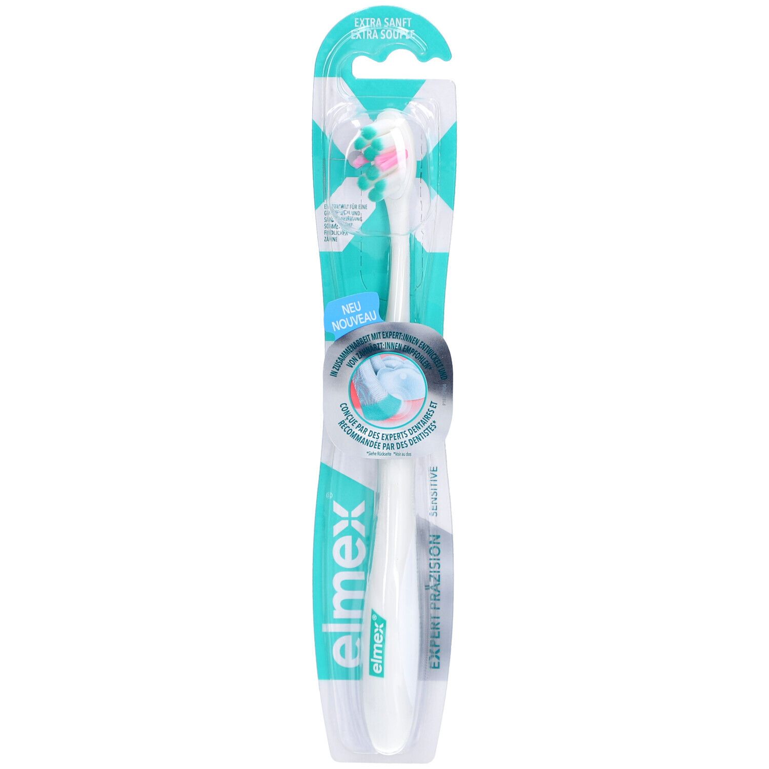 Brosse à dents dans son emballage. Manche blanc, tête de brosse verte et rose. Inscriptions "elmex" et "Expert Präzision".