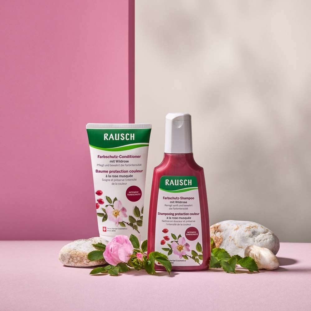 Arrangement de produits: shampooing et après-shampooing à la rose sauvage. Sur fond rose, décoré de pierres et de fleurs.