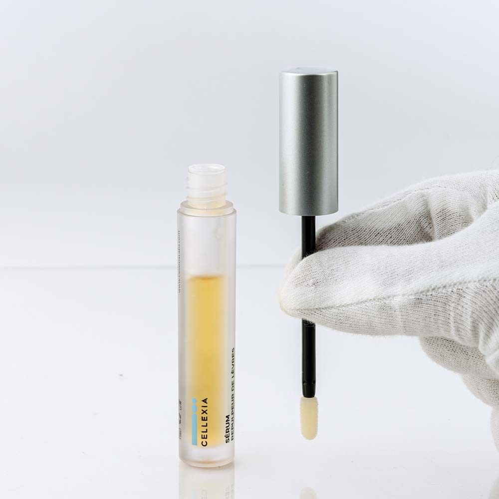 Flacon avec applicateur et liquide jaunâtre. Main gantée de blanc tenant l'applicateur.