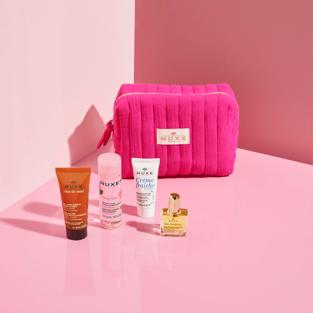 Trousse de toilette rose et produits sur surface rose. Produits NUXE visibles.