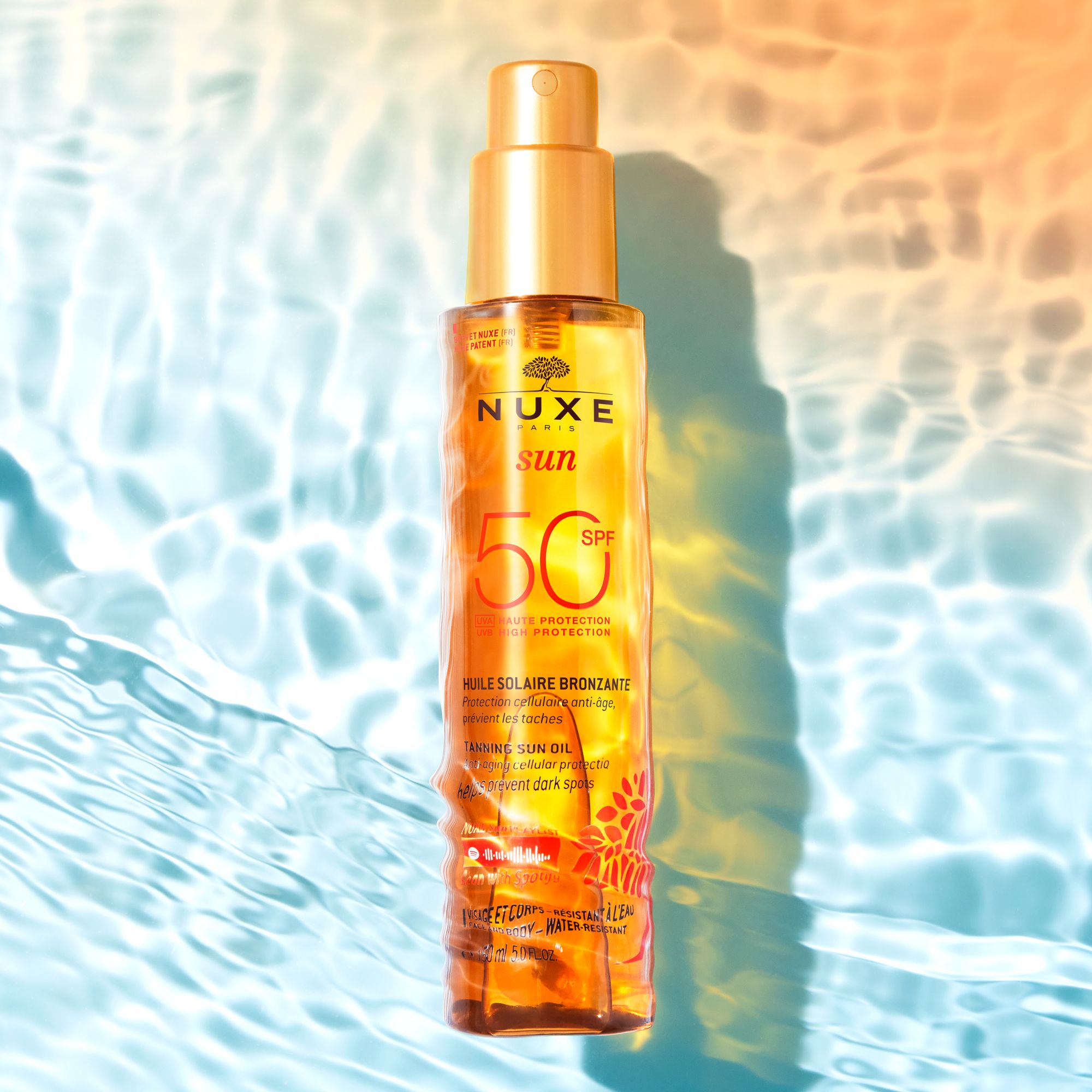 Flacon d'huile NUXE Sun SPF 50. Produit dans l'eau. Étiquette orange.