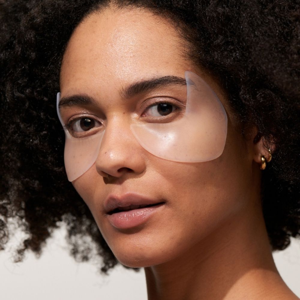 Une femme avec deux coussinets pour les yeux et les tempes sur la peau. Les coussinets sont transparents et couvrent les yeux et les tempes.