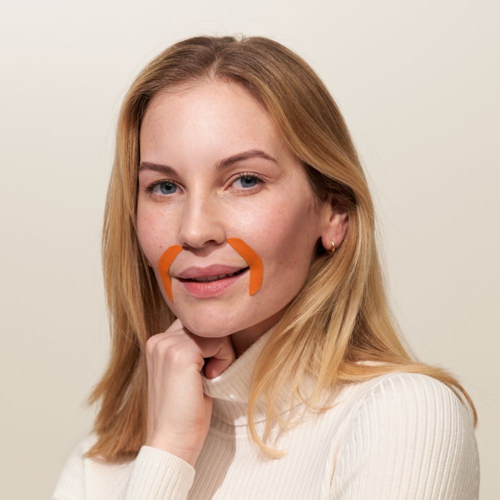 Femme portant deux patchs buccaux APRICOT orange sur les coins de la bouche.